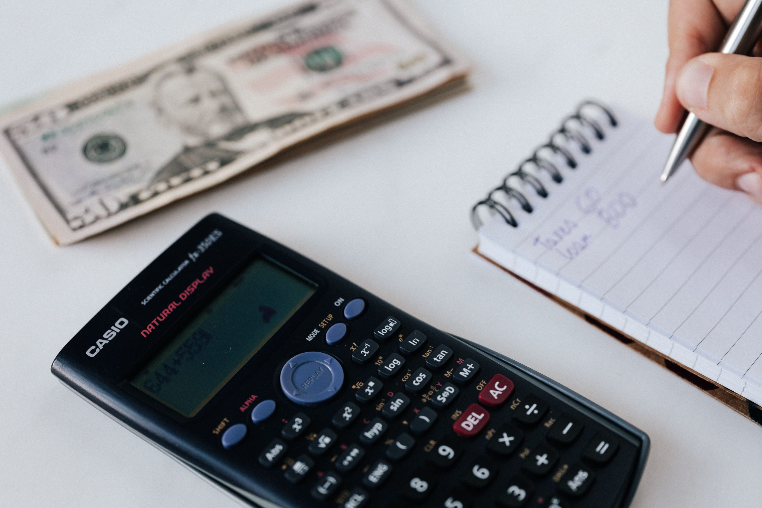 pexels photo 4386325 4386325 1 From above of crop anonymous financier counting profit while writing down information on notepad near pile of paper money on table